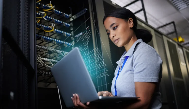 Revolutionize Your IT: Why Smart IT Leaders Are Rethinking Virtualization // Black woman using laptop in data center
